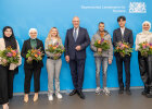 Gruppenfoto mit Innen- und Integrationsminister Joachim Herrmann in der Mitte, links und rechts neu Eingebürgerte mit Blumensträußen