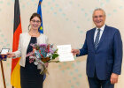 Claudia Junghans mit Bundesverdienstkreuz und Blumenstrauß, neben ihr Innenminister Joachim Herrmann mit Urkunde