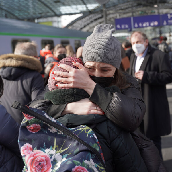 Menschen am Bahnsteig, im Vordergrund zwei sich umarmende Frauen