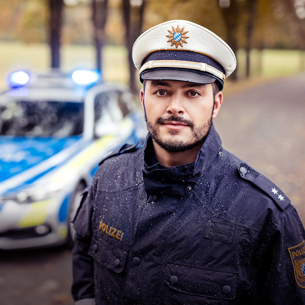 Polizist in Uniform vor Streifenwagen