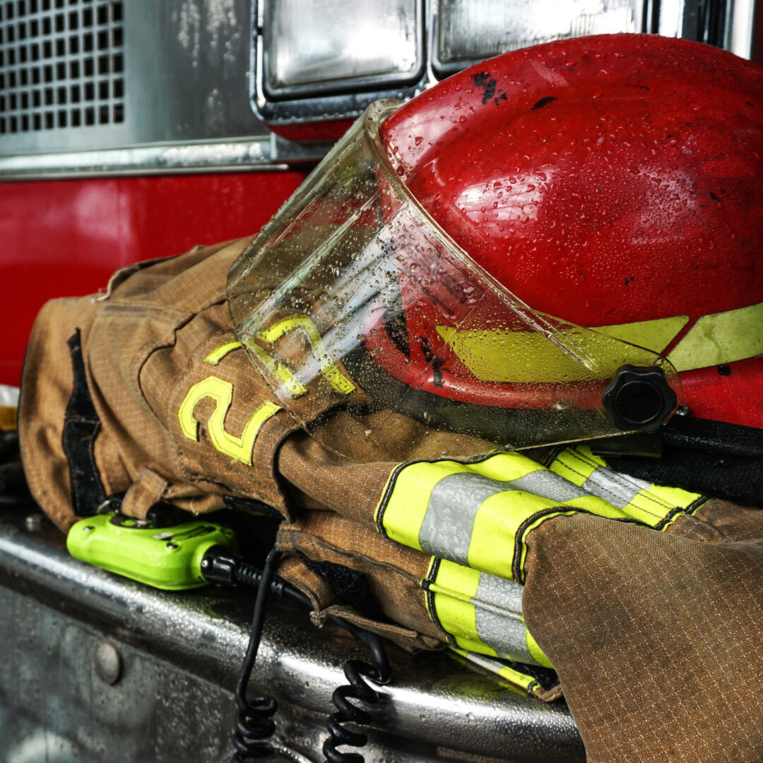 Nahaufnahme: Helm auf Feuerwehrkleidung vor Feuerwehrauto