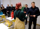 Feuerwehrmann überreicht Schülerin ein Geheft